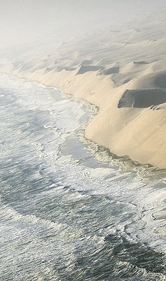 The waves of the Atlantic breaking against the sand cliffs of Namib desert, Namibia